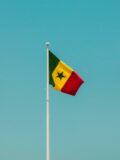 Vibrant Senegalese flag waving on a flagpole against a clear blue sky in Dakar.