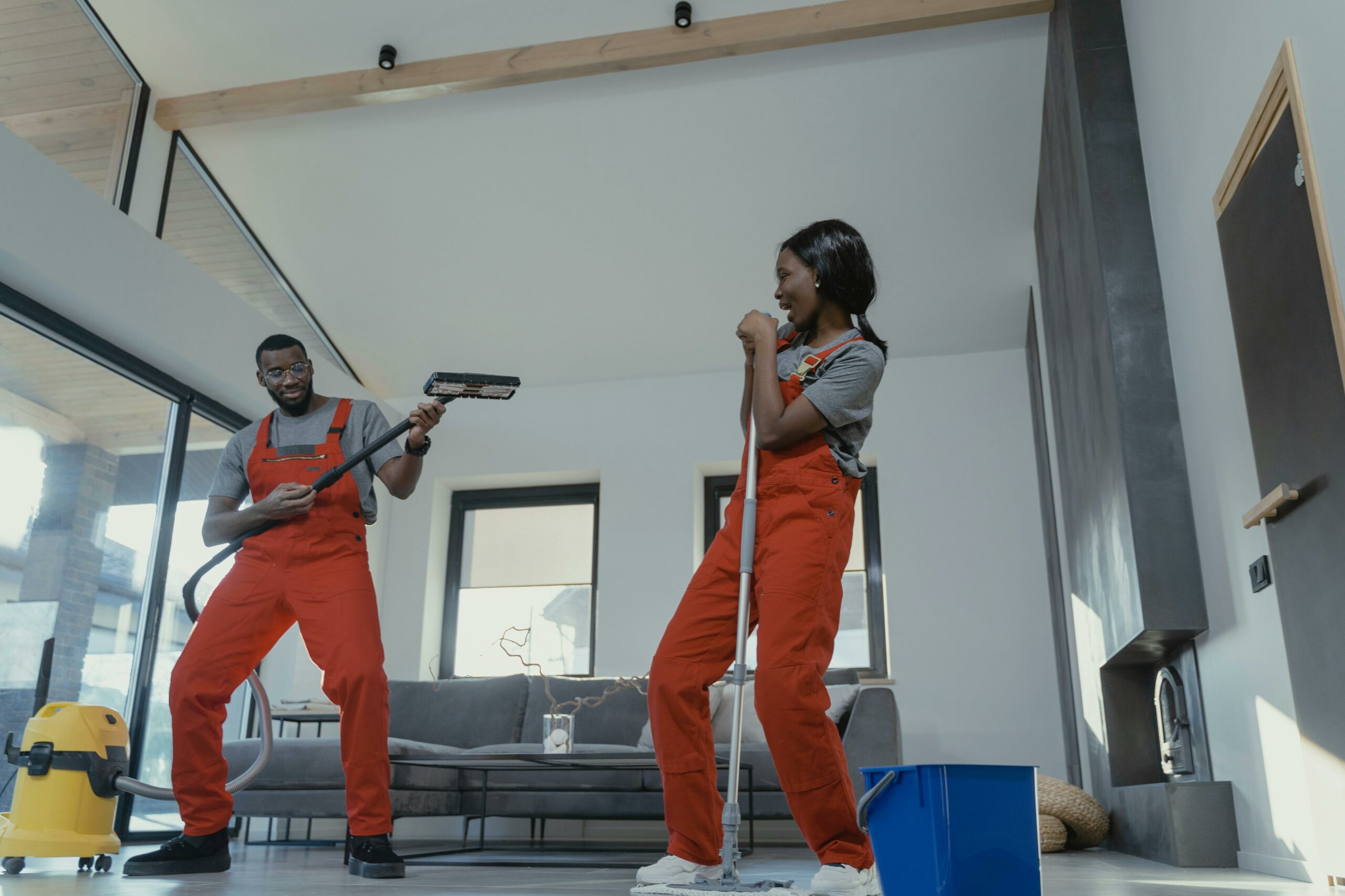 Acceuil Two adults in vibrant coveralls cleaning a modern home interior, enjoying work.